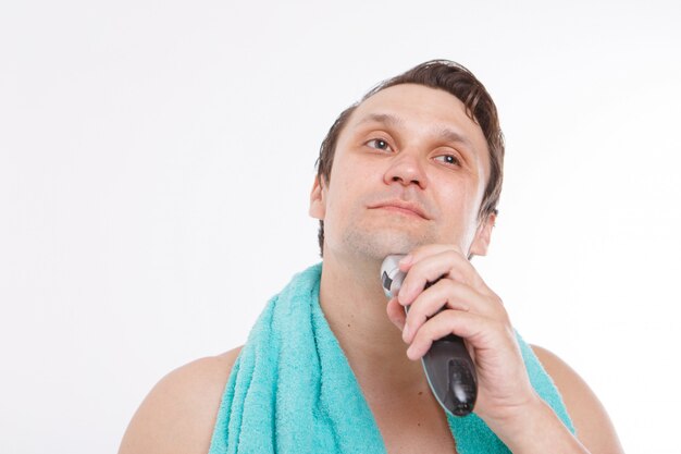człowiek goli swój zarost. facet czyści brodę elektryczną maszynką do golenia. poranne zabiegi w łazience.