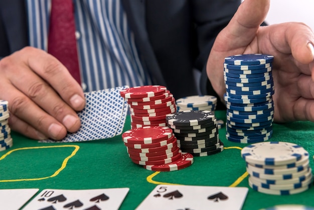 Człowiek gra w kasynie z kartami do gry i żetonami przy zielonym stole. hazard