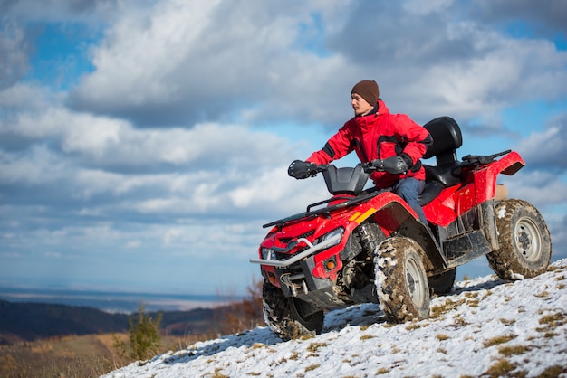 człowiek jedzie na czerwony quad czterokołowy