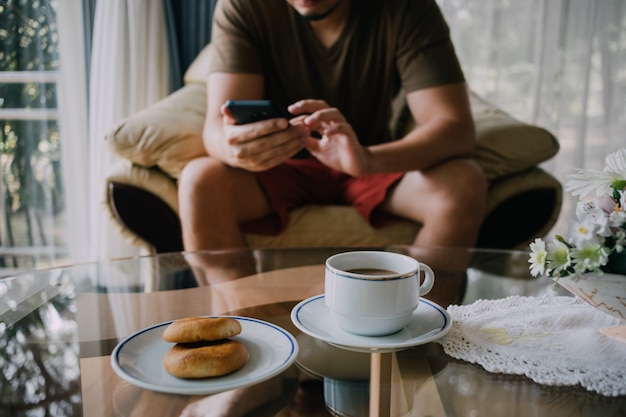 Człowiek korzysta z smartphone i zrelaksować się przy kawie i ciasteczkach.