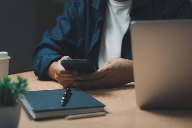 Zdjęcie człowiek korzystający z smartfona komórkowego i pracujący na laptopie komputerze edukacja i technologia student pracujący na własną rękę