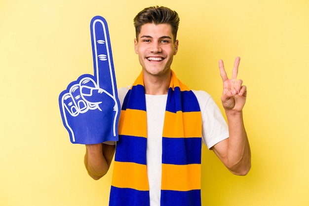 Człowiek młody fan sportu na białym tle na żółtym tle pokazując numer dwa palcami.