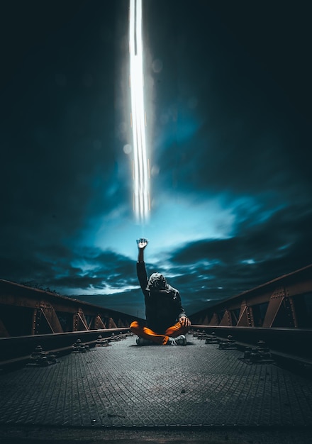 Zdjęcie człowiek na moście wysyłający nocą magiczną moc do nieba