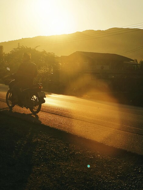 Zdjęcie człowiek na motocyklu na drodze przeciwko niebu podczas zachodu słońca