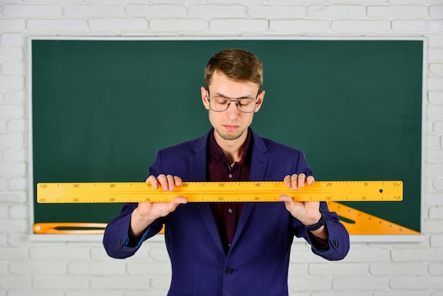 Człowiek nauczyciel na tablicy, trzymając pojęcie tematu matematyki linijki
