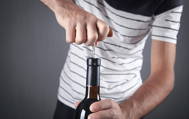 Zdjęcie człowiek otwierając butelkę wina z korkociągiem.