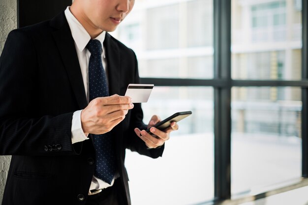 człowiek posiadający kartę kredytową i za pomocą witryny zakupy online za pośrednictwem laptopa i smartphone