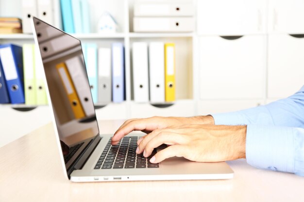 Człowiek pracujący na laptopie na drewnianym stole na tle folderu