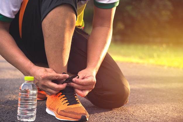 Człowiek przygotowuje i nosi buty sportowe do joggingu i ćwiczeń w godzinach porannych.