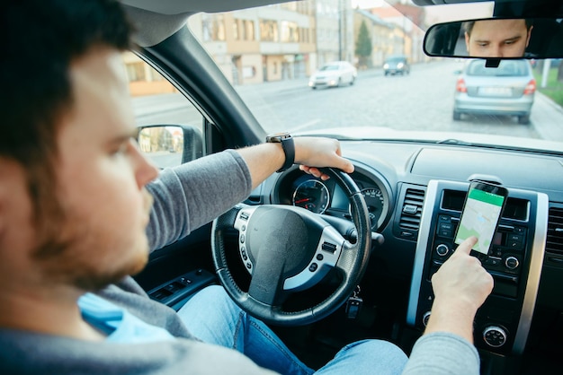 Człowiek ręce na kierownicy przy użyciu telefonu jako nawigatora. podróż samochodem