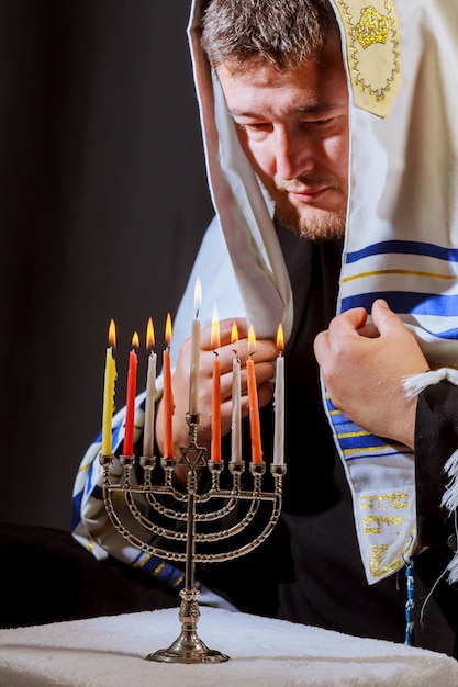 Zdjęcie człowiek ręcznie zapalanie świec w menora na stole serwowane dla hanukka