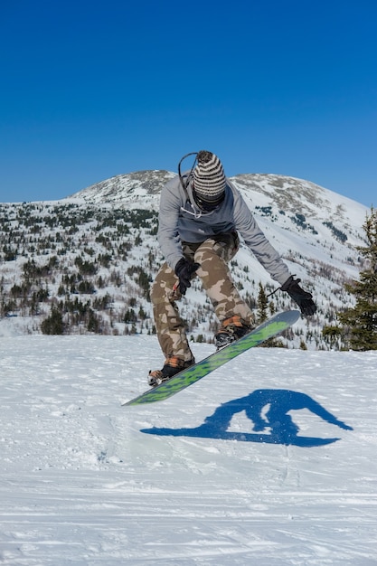 Zdjęcie człowiek robi skok na snowboardzie na tle gór