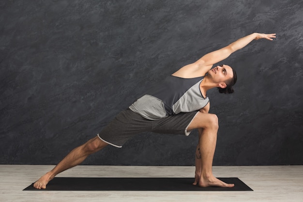 Człowiek, rozciąganie rąk i nóg na macie w siłowni. Sportowiec ćwiczy. Sport, joga, pilates, fitness, koncepcja zdrowego stylu życia