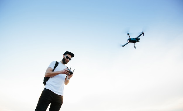 Człowiek sterujący dronem za pomocą kontrolera i latający. człowiek gra z dronem