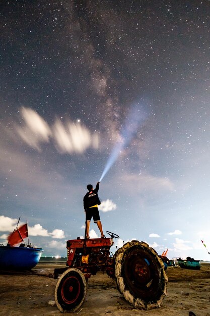 Zdjęcie człowiek stojący na polu przed nocnym niebem