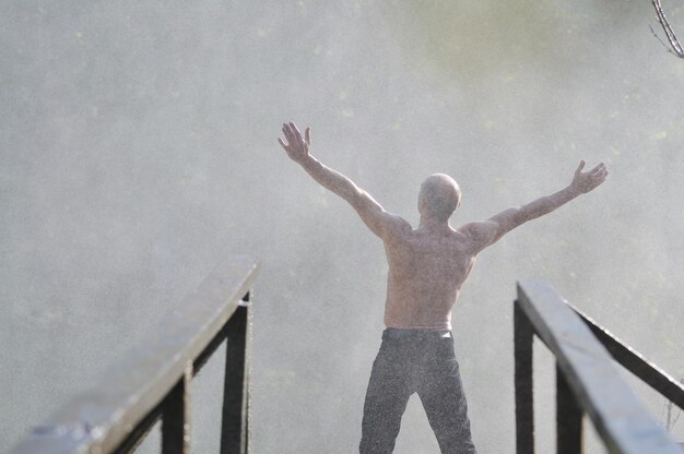 Człowiek stojący z szeroko otwartymi ramionami z wodospadami w tle i reprezentujący świeżość zdrowy styl życia i koncepcja sukcesu
