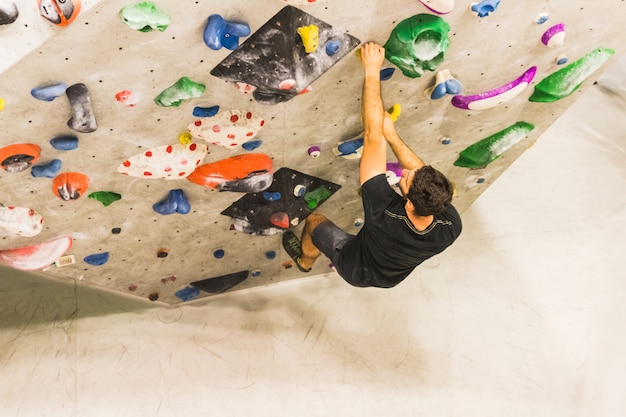 Człowiek uprawiania wspinaczki skałkowej na sztucznej ścianie w pomieszczeniach. Aktywny styl życia i koncepcja boulderingu.