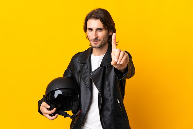 Człowiek w kasku motocyklowym na żółtym tle pokazując i podnosząc palec