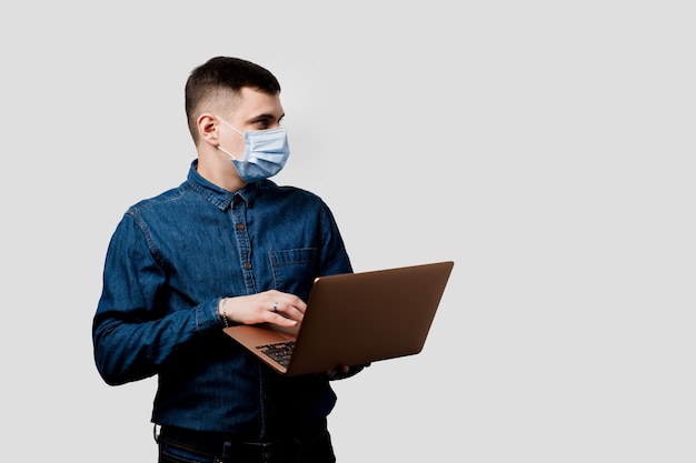 Człowiek w masce chirurgicznej za pomocą laptopa.