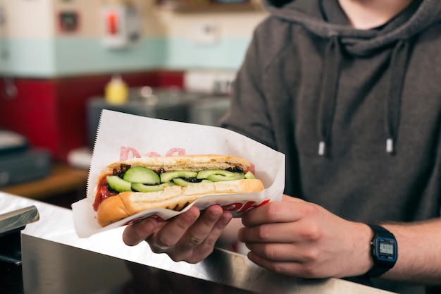 Zdjęcie człowiek z hot-dog w barze przekąskowym fast food