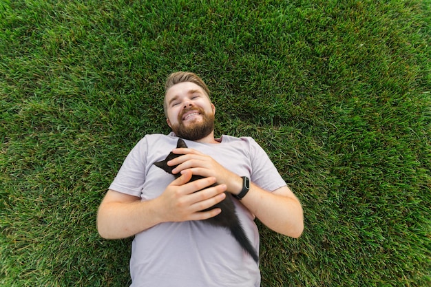 Człowiek z małym kotkiem leżącym i bawiącym się na trawie przyjaźń kocha zwierzęta i koncepcję właściciela zwierzaka