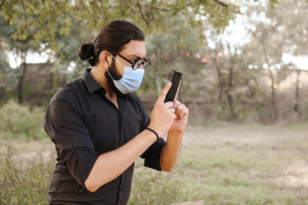 Człowiek Z Maską Ochronną Za Pomocą Telefonu Komórkowego W Naturze