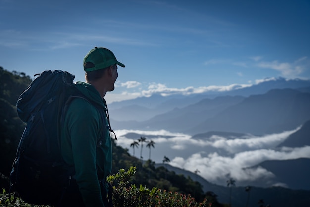 Zdjęcie człowiek z plecakiem patrząc na widok na góry. koncepcja podróży i przygody. zdjęcie wysokiej jakości