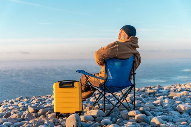 Człowiek z żółtą walizką relaksujący się samotnie na leżakach nad morzem Koncepcja stylu życia w podróży