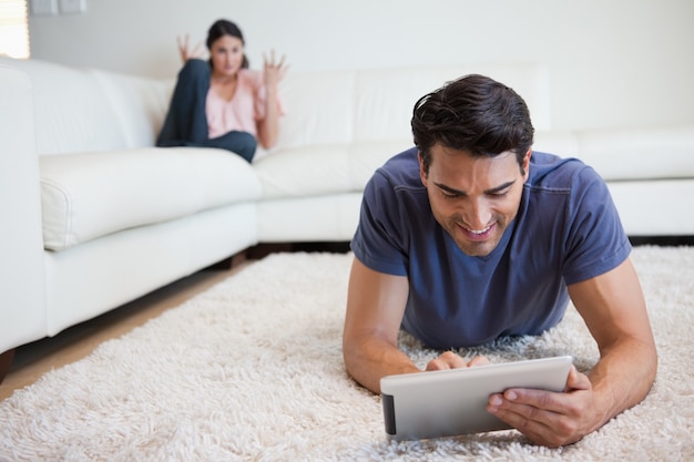 Człowiek za pomocą komputera typu tablet, podczas gdy jego dziewczyna jest na niego wściekła