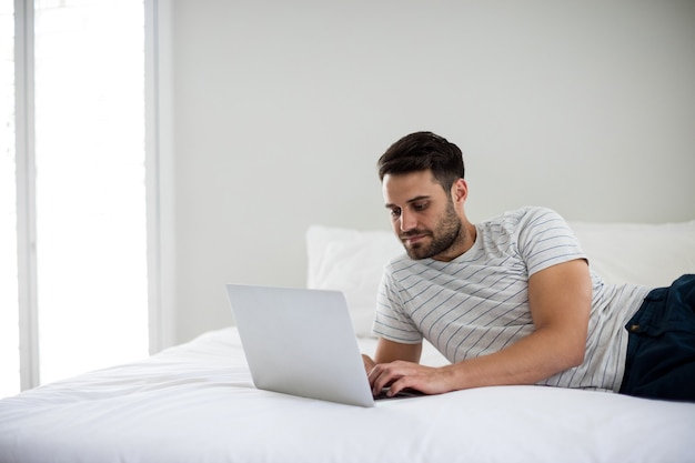 Człowiek za pomocą laptopa na łóżku w sypialni