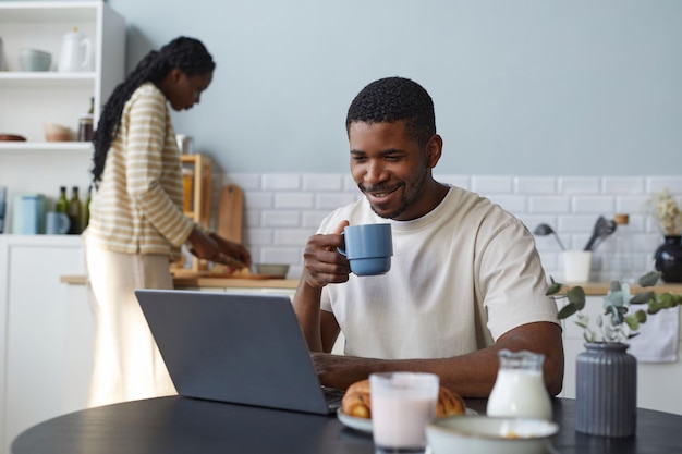 Człowiek za pomocą laptopa podczas śniadania w domu