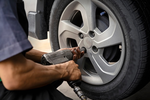 Zdjęcie człowiek za pomocą mechanika samochodowego zablokuj koło wiatru. sprawdzenie opon i hamulca samochodu. mechanik samochodowy przygotowanie do pracy.