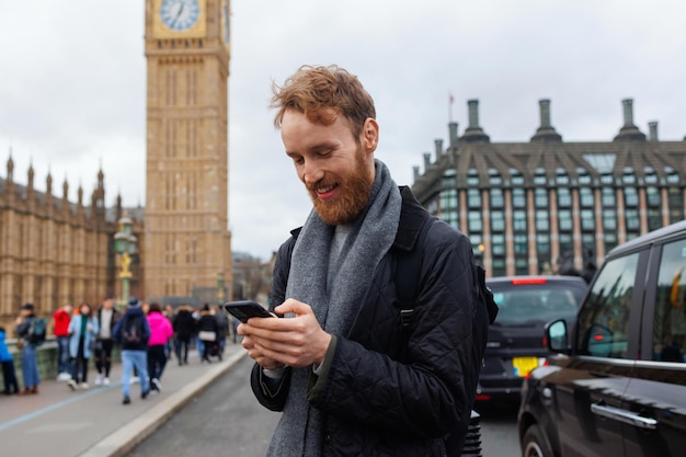 Człowiek za pomocą smartfona na tle londyńskiej wieży Big Ben