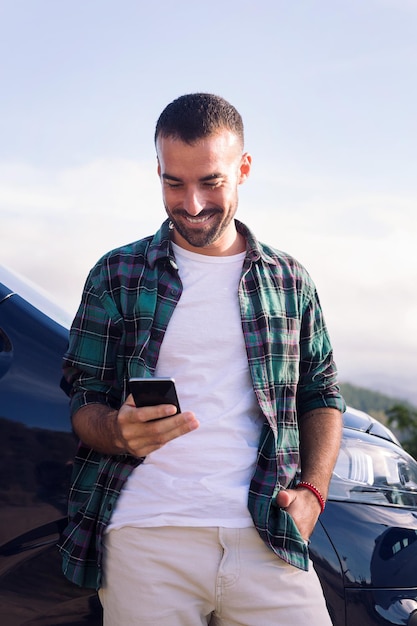 Człowiek za pomocą telefonu komórkowego, opierając się na jego samochód kempingowy