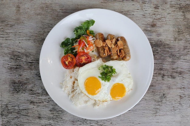 Czosnek Pepper Longaniza ze słonecznym jajkiem i ryżem z pomidorem z sałatką podawany w naczyniu odizolowanym na drewnianym tle widok z góry śniadania