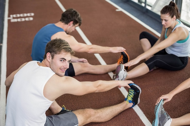 Cztery atletyczne kobiety i mężczyźni rozciągający się na bieżni