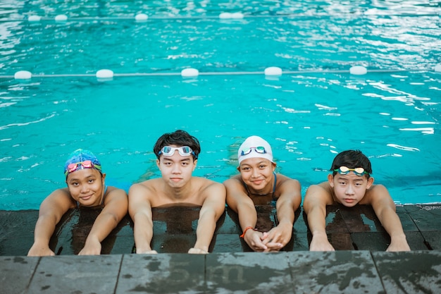 Cztery Azjatyckie Nastolatki W Strojach Kąpielowych Uśmiechają Się Do Kamery Podczas Odpoczynku Przy Basenie?