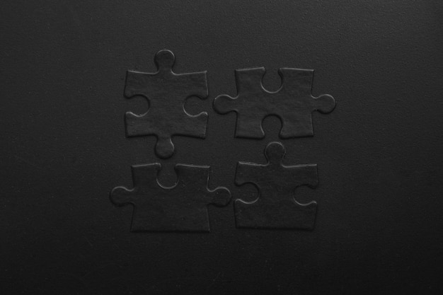 Zdjęcie cztery czarne puzzle na ciemnym tle