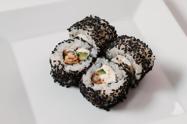 Cztery czarne rolki sushi maki ozdobione zielenią