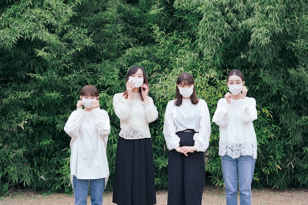 Cztery młode Japonki ubrane w białe koszule i maski na zewnątrz