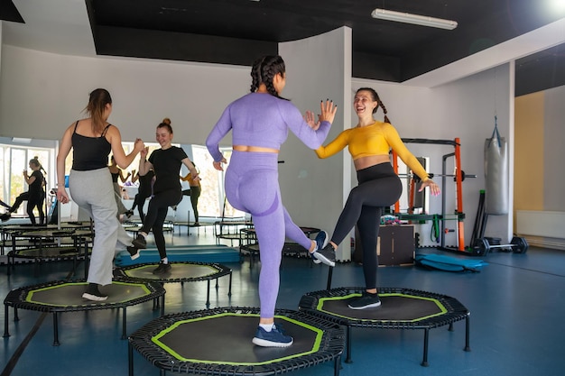 Cztery młode kobiety na trampolinie młode dziewczyny fitness trenują w studio fitness