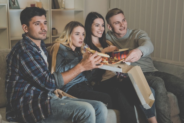 Cztery Osoby Jedzą Pizzę I Oglądają Film Na Kanapie