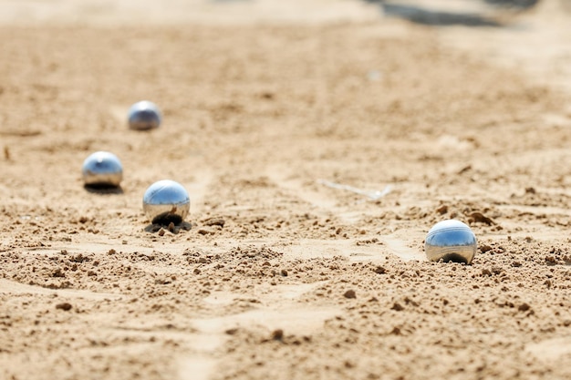 Zdjęcie cztery srebrne kule leżą na piasku morskiej plaży, odbijając niebo