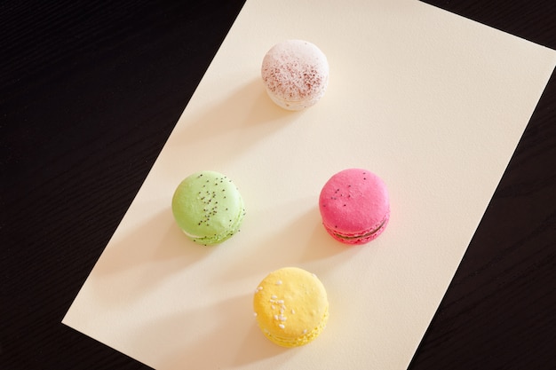 Cztery wielokolorowe macarons na żółtym arkuszu papieru