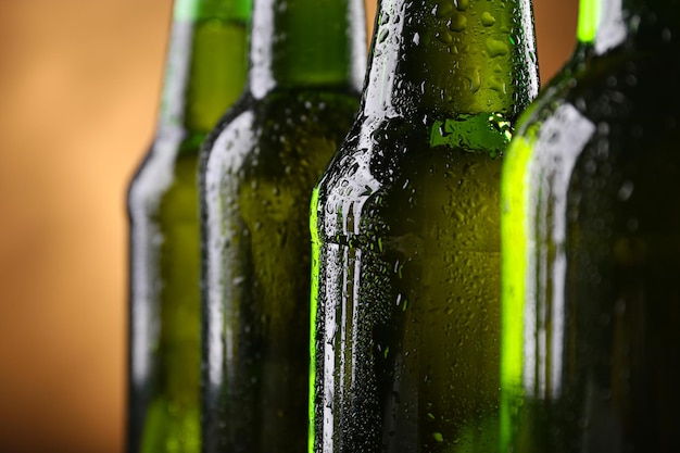 Zdjęcie cztery zielone szklane butelki piwa na ciemnym oświetlonym tle z bliska