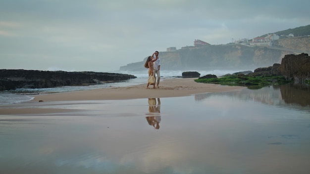 Czulna para obejmująca plażę z chmurnym niebem nieznany mężczyzna kręci się kobieta tańczy