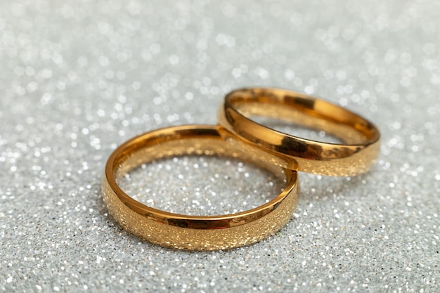 Czy wyjdziesz za mnie dwie złote obrączki na srebrnym brokatowym tle zaręczynowej propozycji małżeństwa