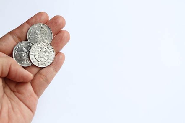 Czyjeś palce trzymające trzy monety indonezyjskich starych monet 25 centów Rupia z 1957 r.