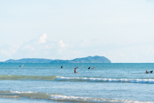 Czyste morze z surferem w wodzie podczas oczekiwania na fale / plażę surfingową / letnią aktywność