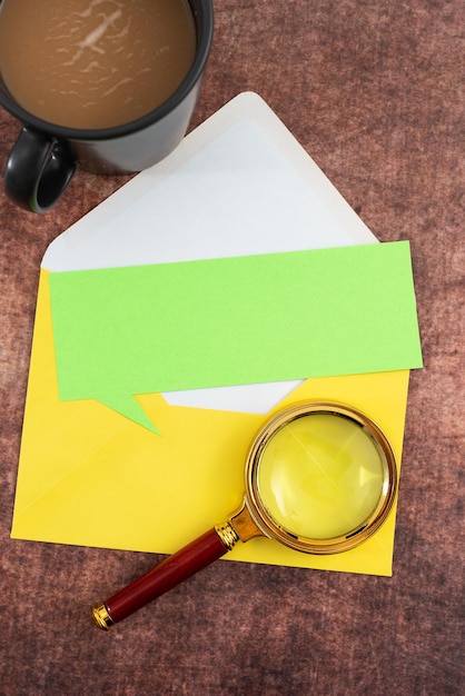 Zdjęcie czysty papier w kształcie dymka koperta kubek do kawy i szkło powiększające umieszczone na stole reprezentuje ważne strategie marketingowe dla celów biznesowych